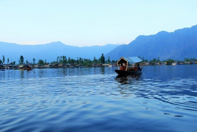 Shikara boat floating on Dal Lake with mountains in background — Dal Lake shikara ride